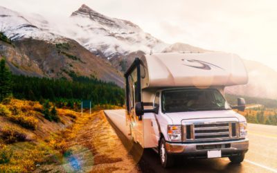 RV parked along roadside with snowy mountains in background.