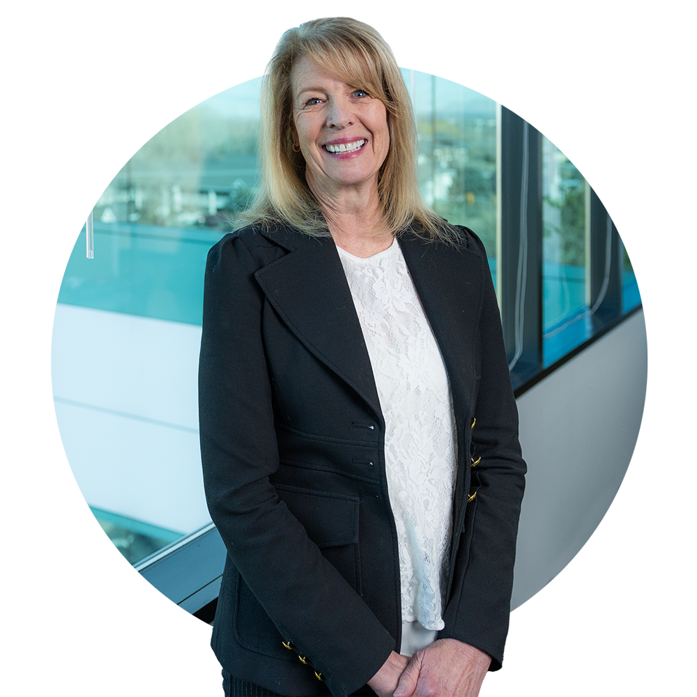 A female member of the recreation sales team, dressed in professional attire, stands in a conference room.She is smiling and looking toward the camera.