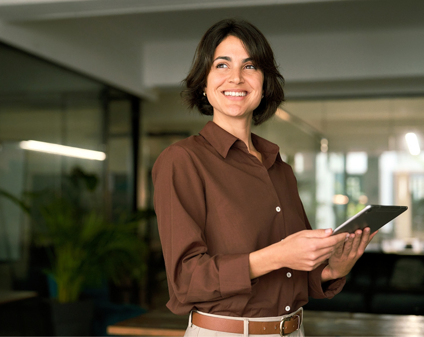 A smiling, dark-haired woman holds her iPad.